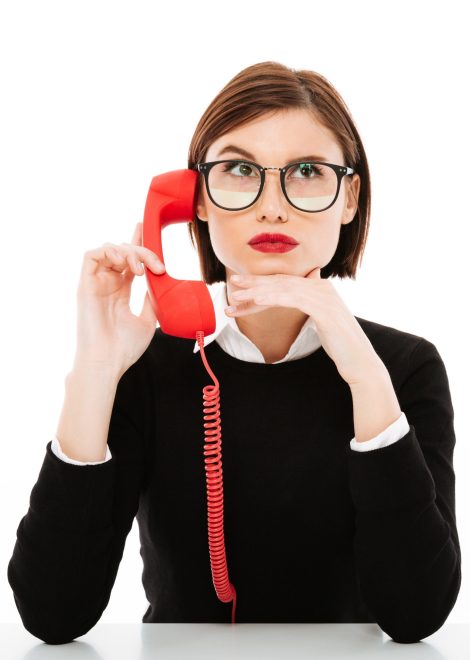 young-businesswoman-talking-by-phone-raising-eyebrow